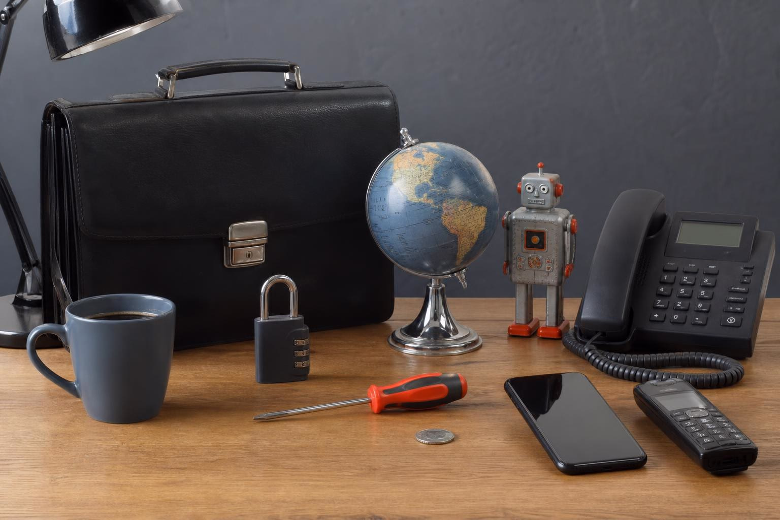 KDB Tech-Update 202607100504 Schreibtisch mit Aktentasche, Globus, Roboterfigur, Vorhängeschloss, Münze, Werkzeug, Telefonanlage und Mobiltelefonen zur Darstellung von Technik und Sicherheit.